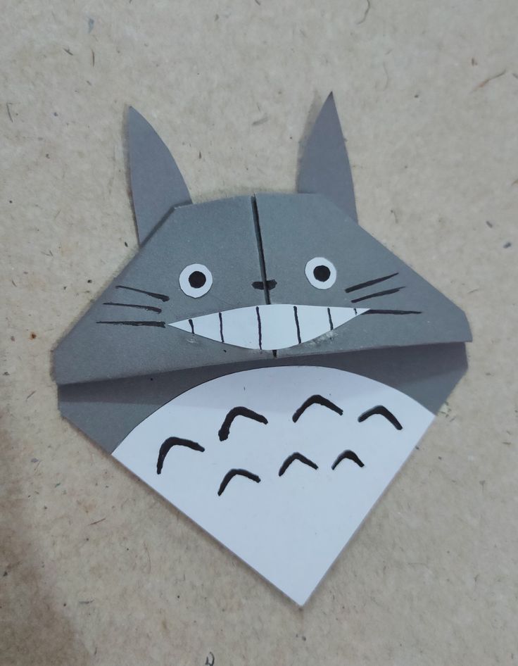 an origami cat made out of paper with eyes and nose drawn on it