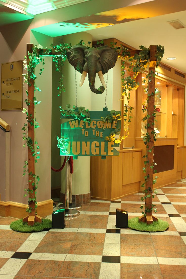 the entrance to an office decorated with greenery and hanging elephant heads on it's walls