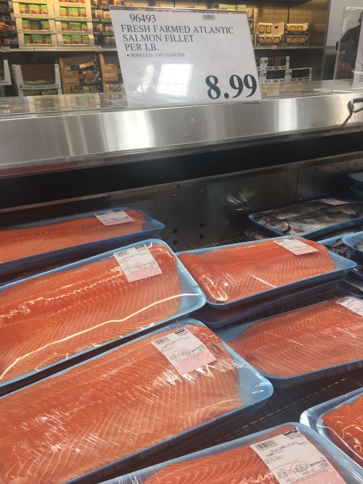 salmon fillets are on display in a grocery store's deli section, with the price sign above them