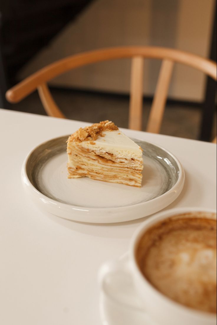 a piece of cake sitting on top of a plate next to a cup of coffee