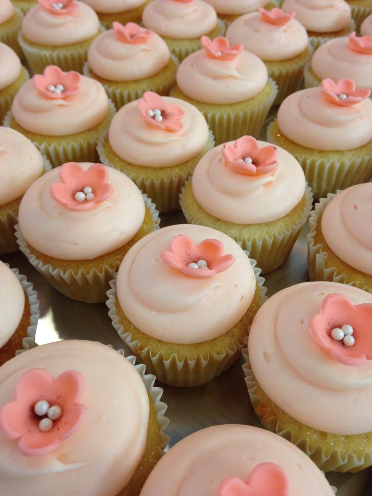 there are many cupcakes with pink and white frosting on them in the box