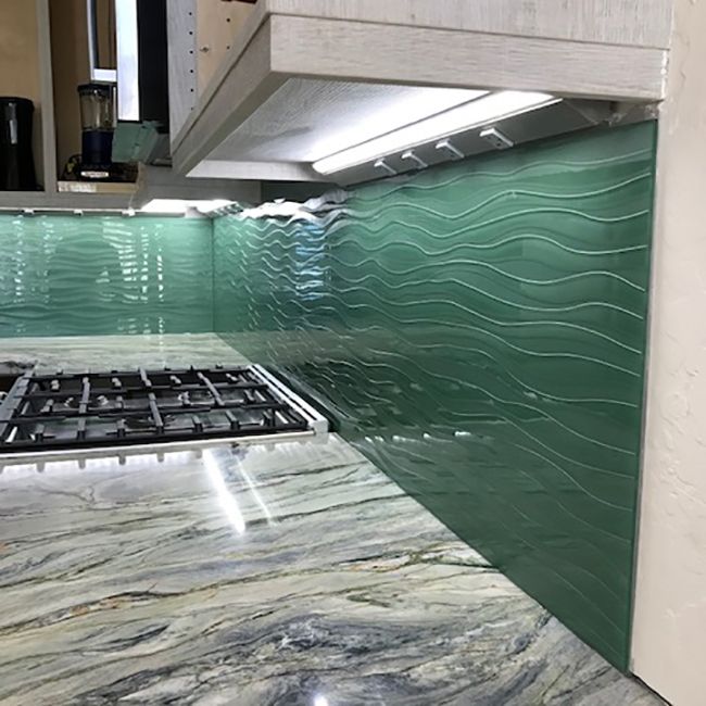 a stove top oven sitting inside of a kitchen next to a counter with green tiles on it