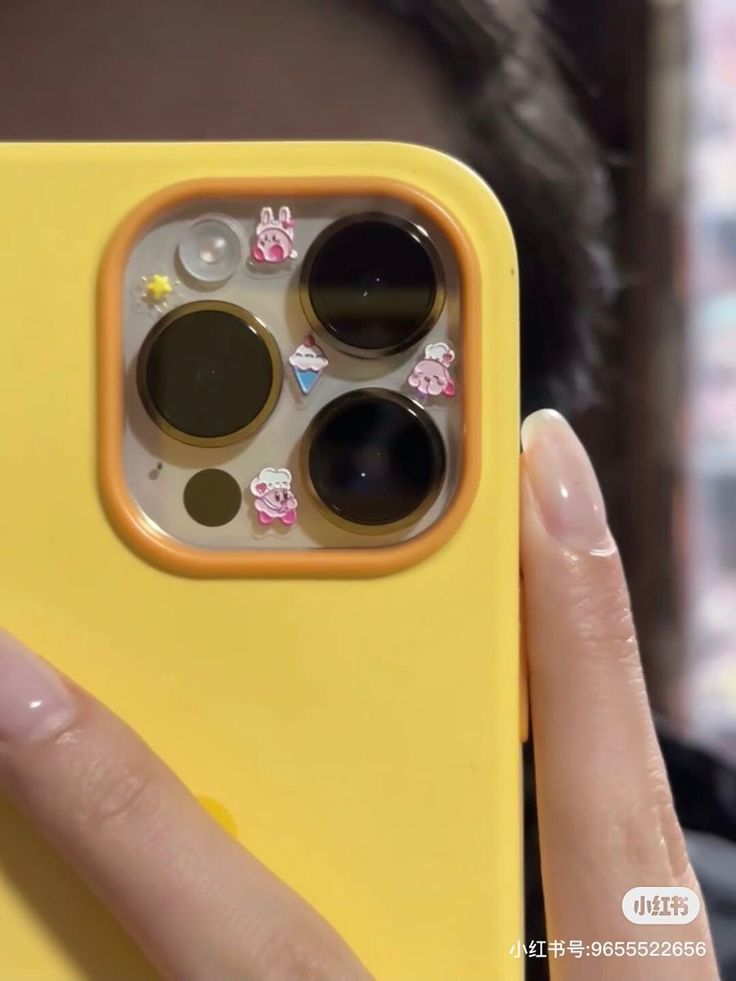 a person holding up a yellow phone case with buttons on the front and bottom sides