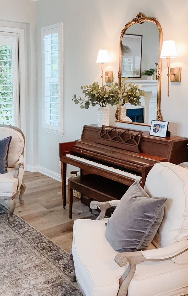 a living room filled with furniture and a piano in front of a mirror on the wall