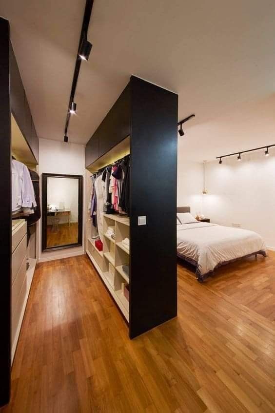 an open closet in the middle of a room with a bed and clothes on shelves