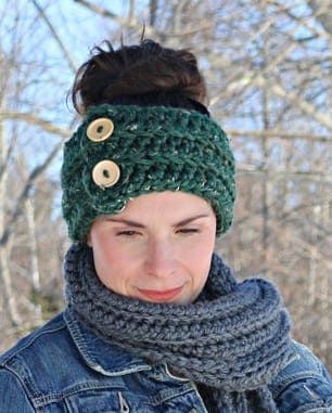 a woman wearing a green knitted hat and scarf with buttons on it's head