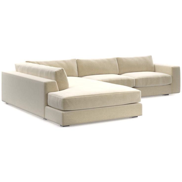 a white sectional couch sitting on top of a white floor next to a chair and ottoman