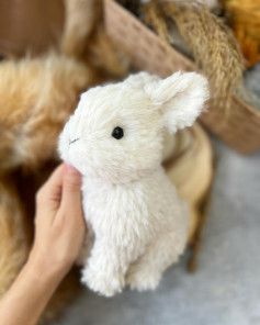 a person holding a small stuffed animal in their hand next to several other stuffed animals