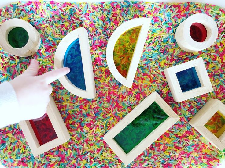 a child's hand pointing at some colorful shapes on a table with sprinkles