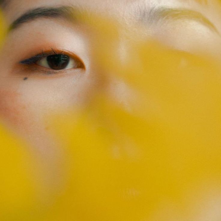 a close up of a woman's face with yellow paint on her cheek and eyes