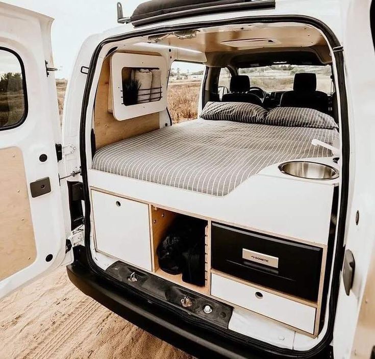 the interior of a camper van with its door open and bed in the back