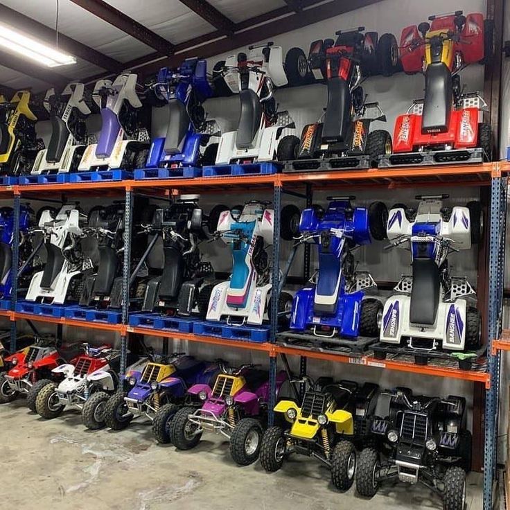 several rows of toy cars and atvs on display in a storage room with orange shelves