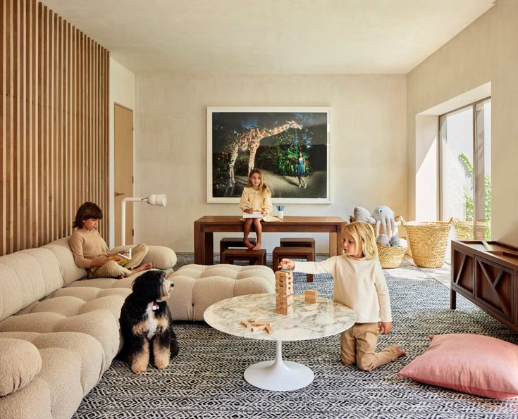 two children and a dog are sitting in the living room with their toys on the coffee table