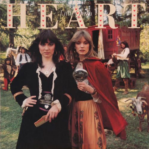 two women standing next to each other on the cover of heart magazine, with people dressed in costume