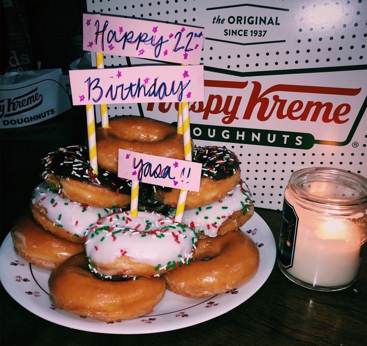 doughnuts are stacked on top of each other in front of a happy birthday sign