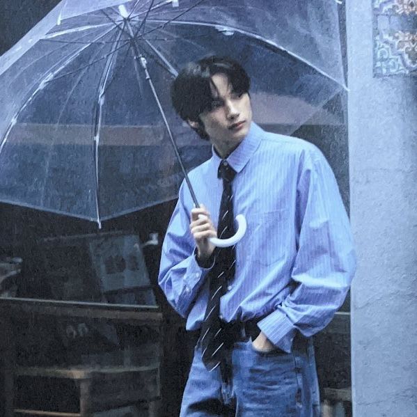 a man in blue shirt and tie holding an umbrella