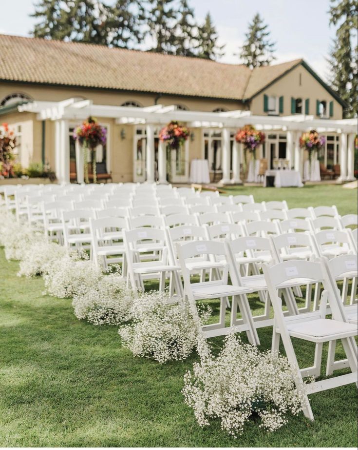 rows of white folding chairs lined up in front of a building with flowers on them