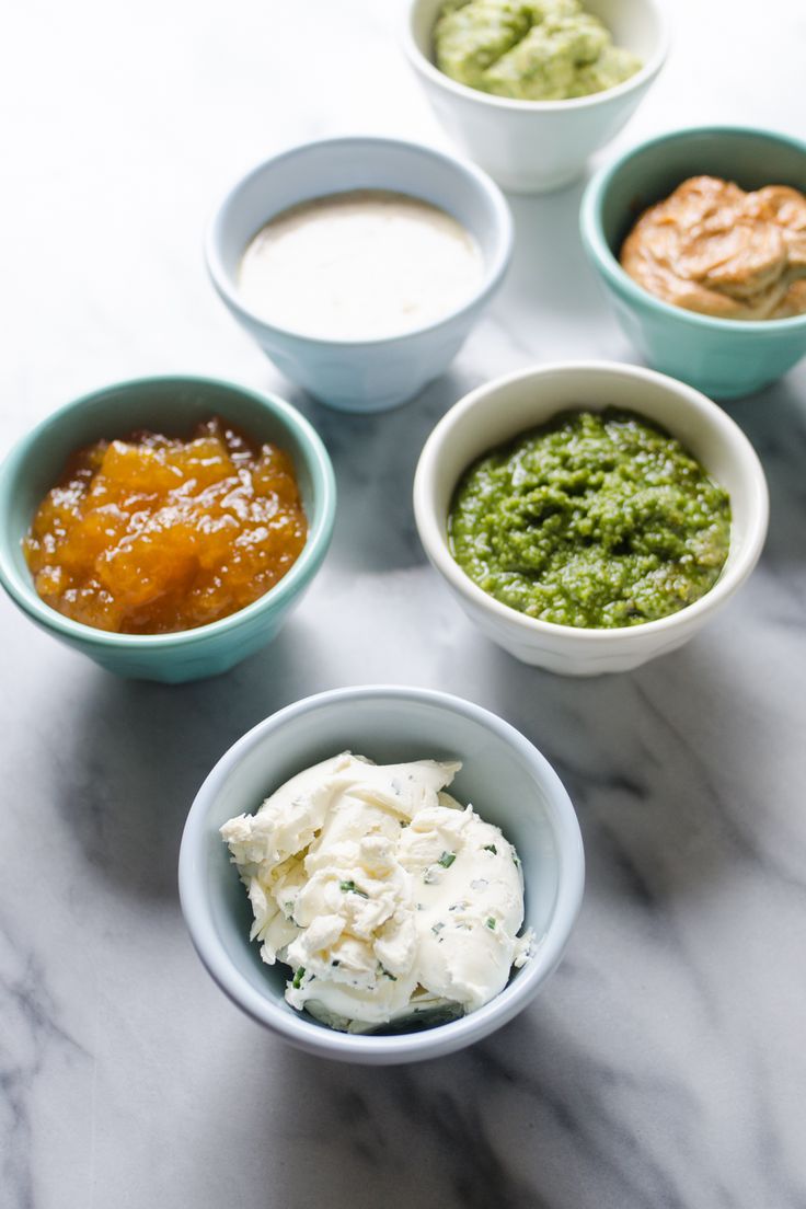 four bowls with different types of food in them on a marble counter top, one bowl is filled with sauce and the other two are empty