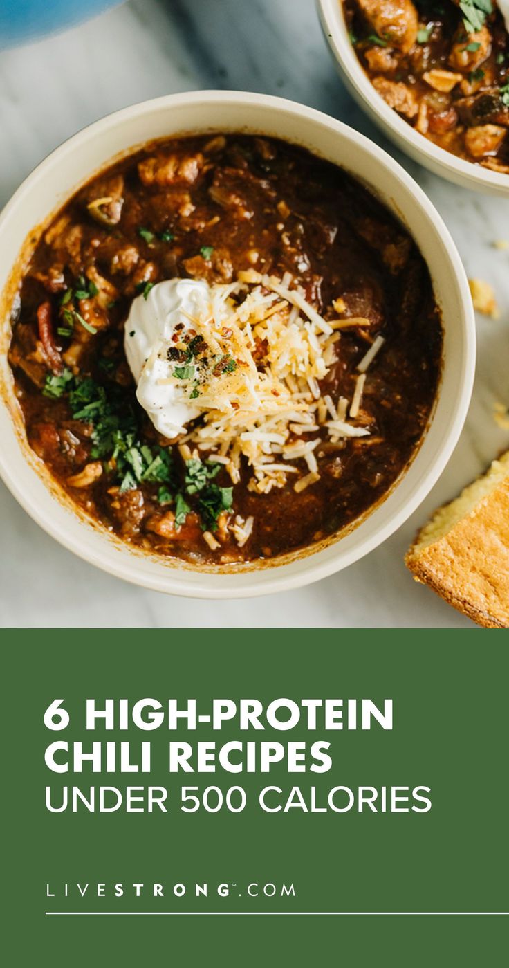 two bowls filled with chili and cheese next to toasted bread on a white table