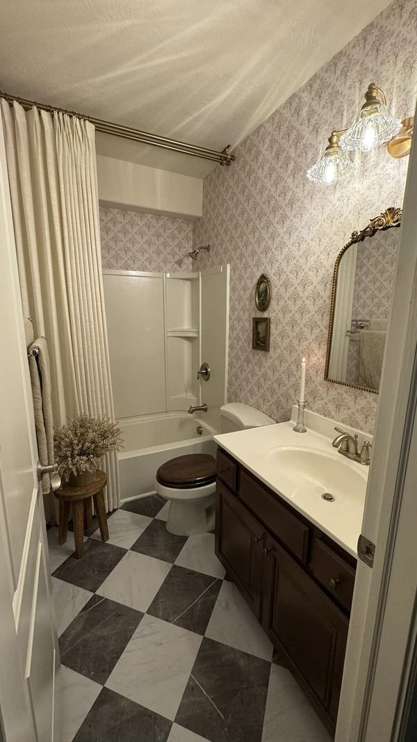 a bathroom with black and white checkered flooring on the walls, shower curtain, toilet, sink, mirror and bathtub