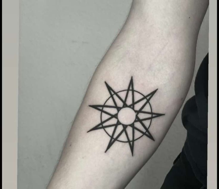 a black and white photo of a person's arm with a compass tattoo on it