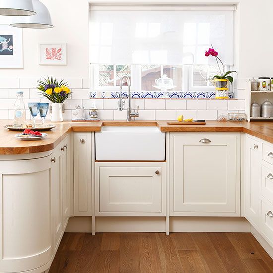 a kitchen with white cabinets and wooden counter tops