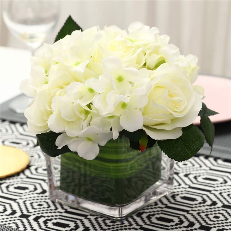 a vase filled with white flowers on top of a black and white tablecloth covered table