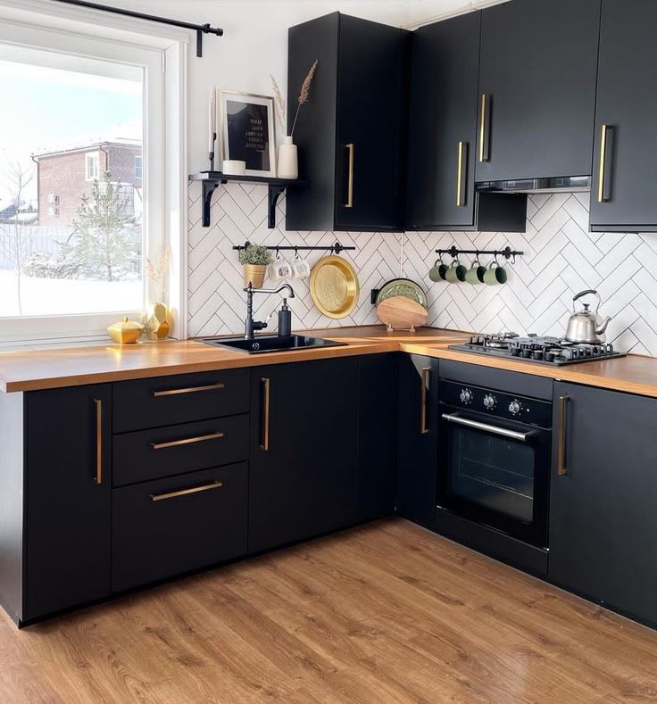 a kitchen with wooden floors and black cabinets