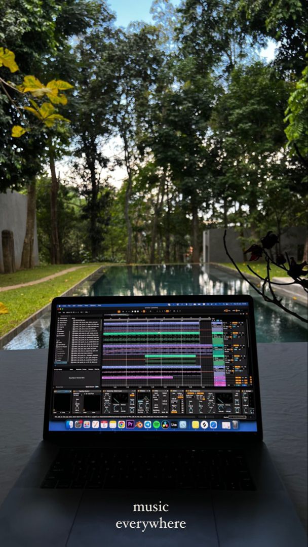 an open laptop computer sitting on top of a table in front of a swimming pool