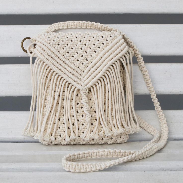 a crocheted white purse sitting on top of a wooden bench next to a wall