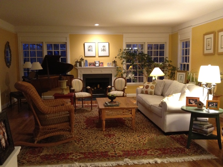 a living room filled with furniture and a piano in the corner on top of a rug