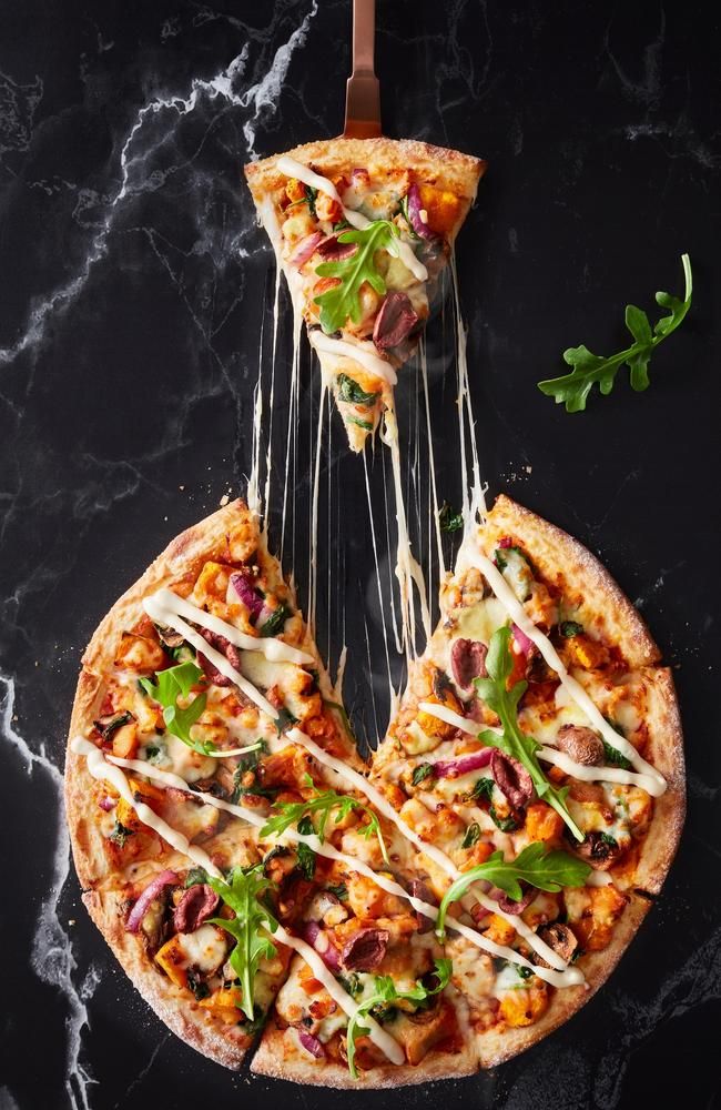 two slices of pizza are being lifted from the air by strings on a black surface