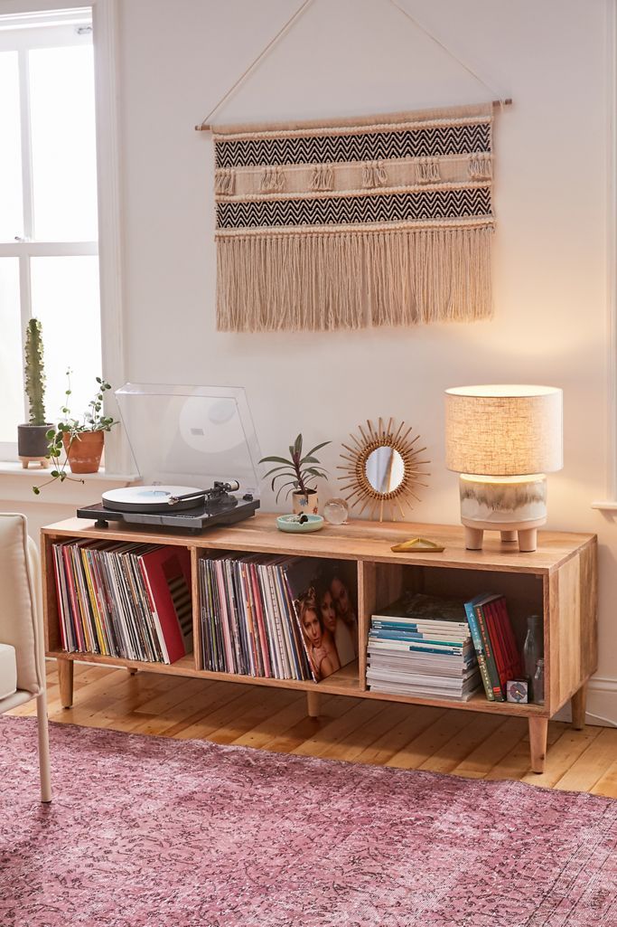 a room with a book shelf, record player and lamp on the side table in front of it