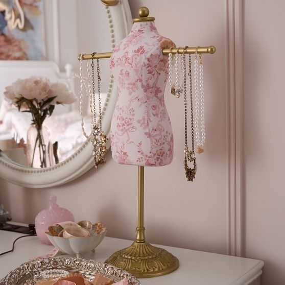 a mannequin is sitting on a table next to a mirror and jewelry tray