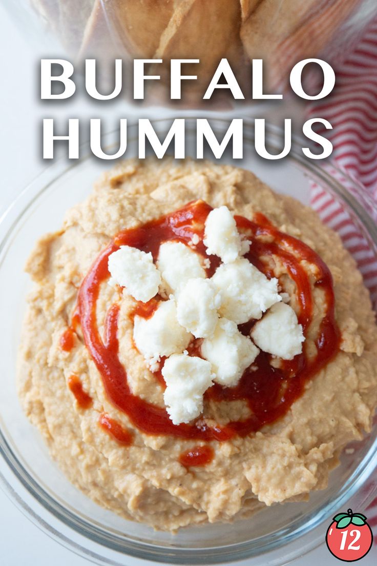 hummus in a glass bowl with cheese and ketchup on top, next to pita chips