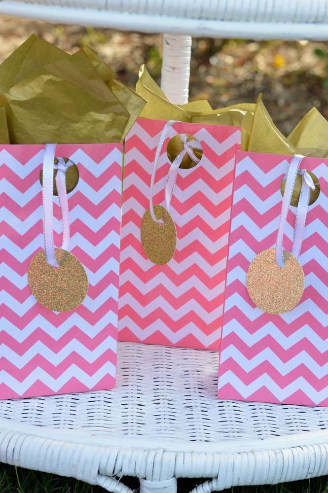 pink and white chevron paper bags with gold polka dots on them sitting on a wicker chair