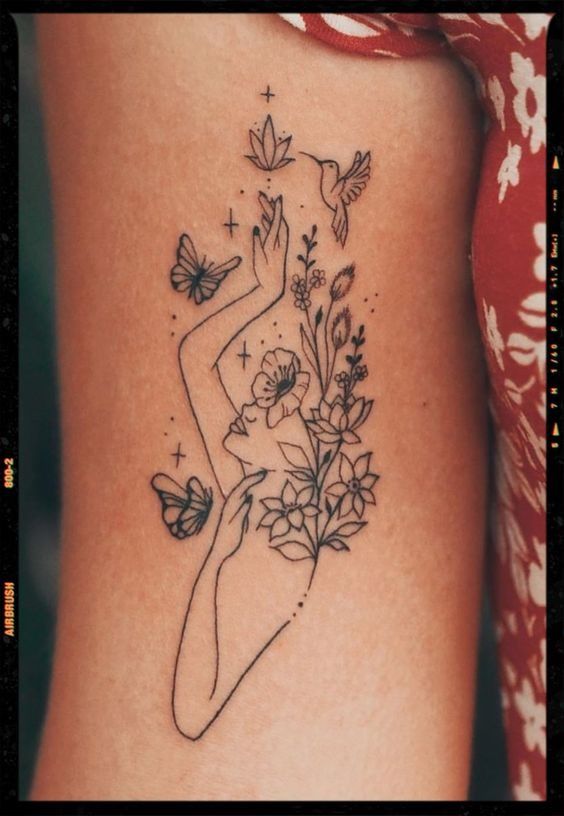 a woman with flowers and butterflies tattoo on her side ribcage, which is drawn in black ink