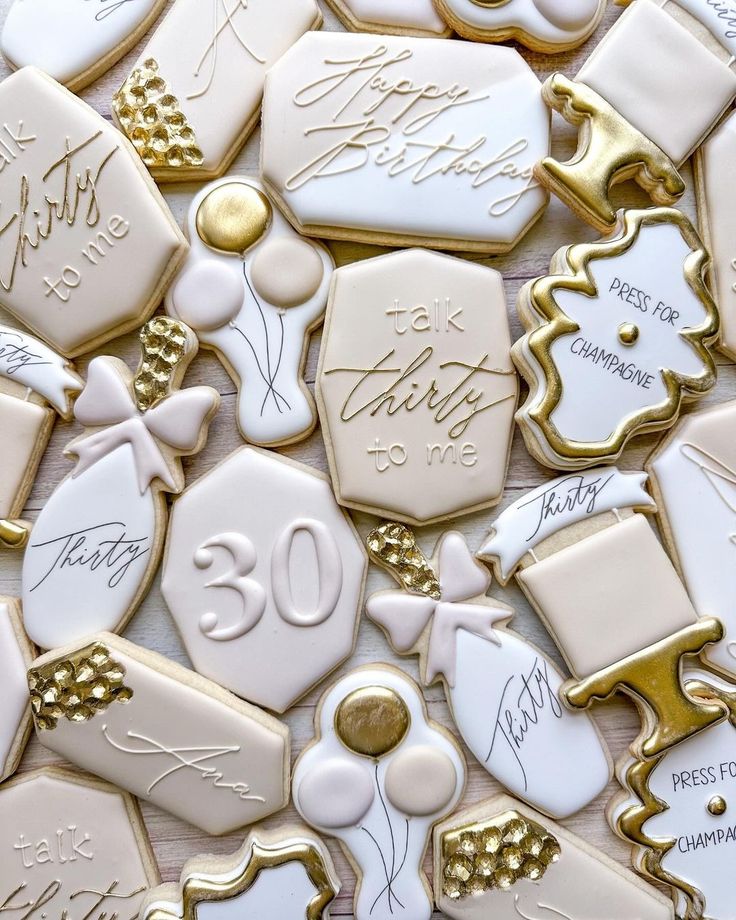 white and gold decorated cookies with the number 30 written on one cookie, surrounded by golden trimmings