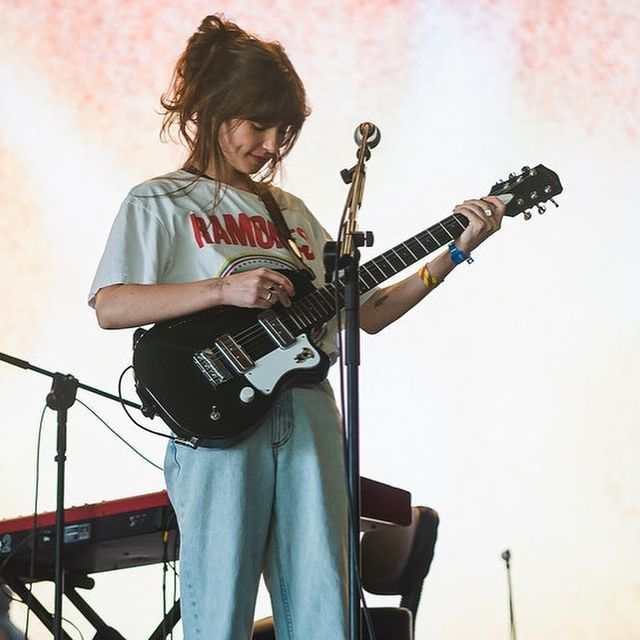 a woman playing an electric guitar on stage