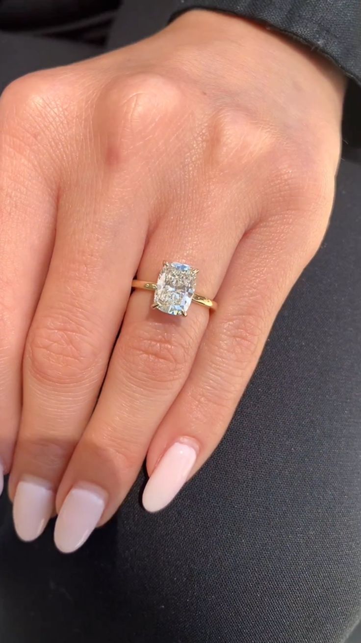 a woman's hand with a ring on top of her finger and a diamond in the middle