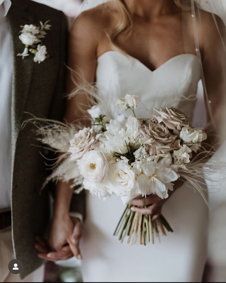 the bride and groom are holding each other's hands while they hold their bouquets