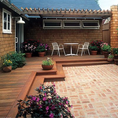 an outdoor patio with potted plants and flowers on the ground next to a house