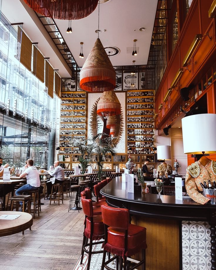 people sitting at tables in a restaurant with lots of bottles on the walls