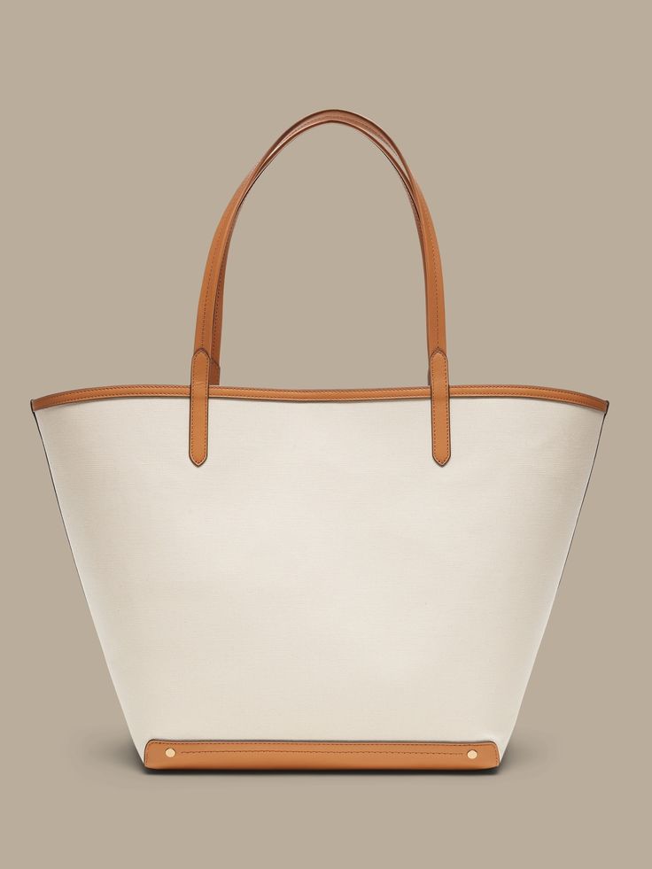 An elegant companion to everyday style, this classic tote goes anywhere with ease with spacious storage, sturdy leather trim, and a snap closure.  Sturdy leather handles.  Open top with snap closure.  Height: 16" (41cm) Width: 25" (63cm) Depth: 8" (2 Everyday Double Handle Bucket Bag With Canvas Lining, Everyday Bucket Bag With Double Handle And Canvas Lining, Shopping Canvas Tote Bag With Handle Drop, Bucket Canvas Bag With Handle Drop, Canvas Bucket Bag With Handle Drop, Large Capacity Coated Canvas Bucket Bag For Shopping, Coated Canvas Bucket Bag For Shopping, Chic Coated Canvas Bucket Bag For Shopping, Everyday Canvas Bucket Bag With Double Handle