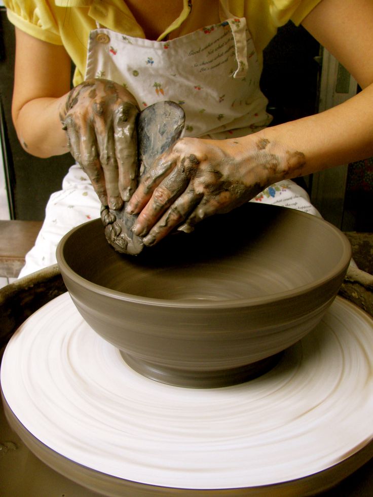 a woman is making clay on a potter's wheel