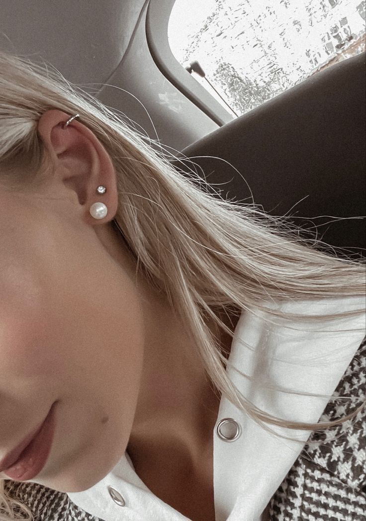 a woman with blonde hair wearing a jacket and pearl earrings