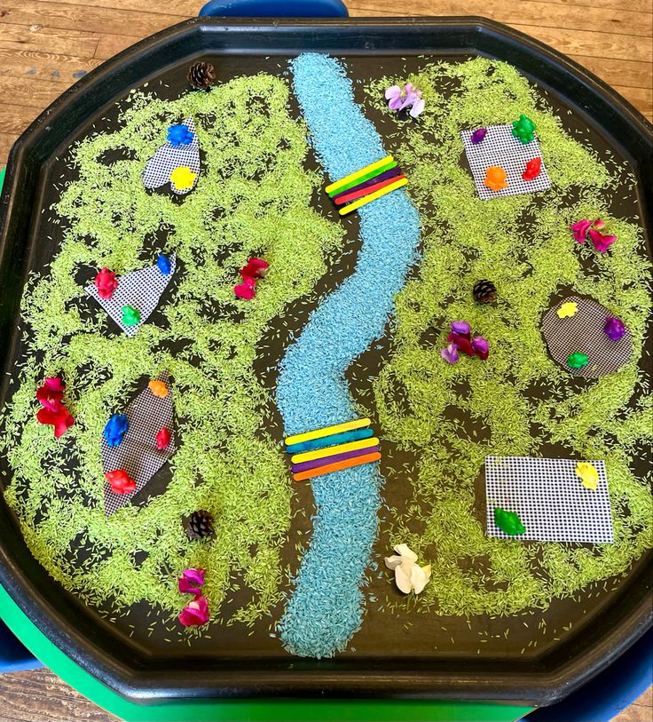 a child's play tray with legos on the grass and water in it