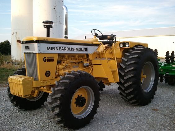 a large yellow tractor parked next to a white silo