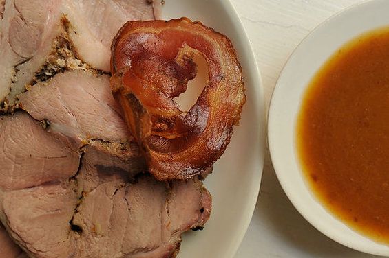 a plate with some meat and sauce on it next to a bowl of tomato soup