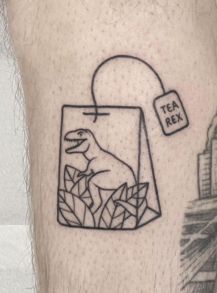 a man's leg with a dinosaur in a shopping bag tattoo on his left thigh